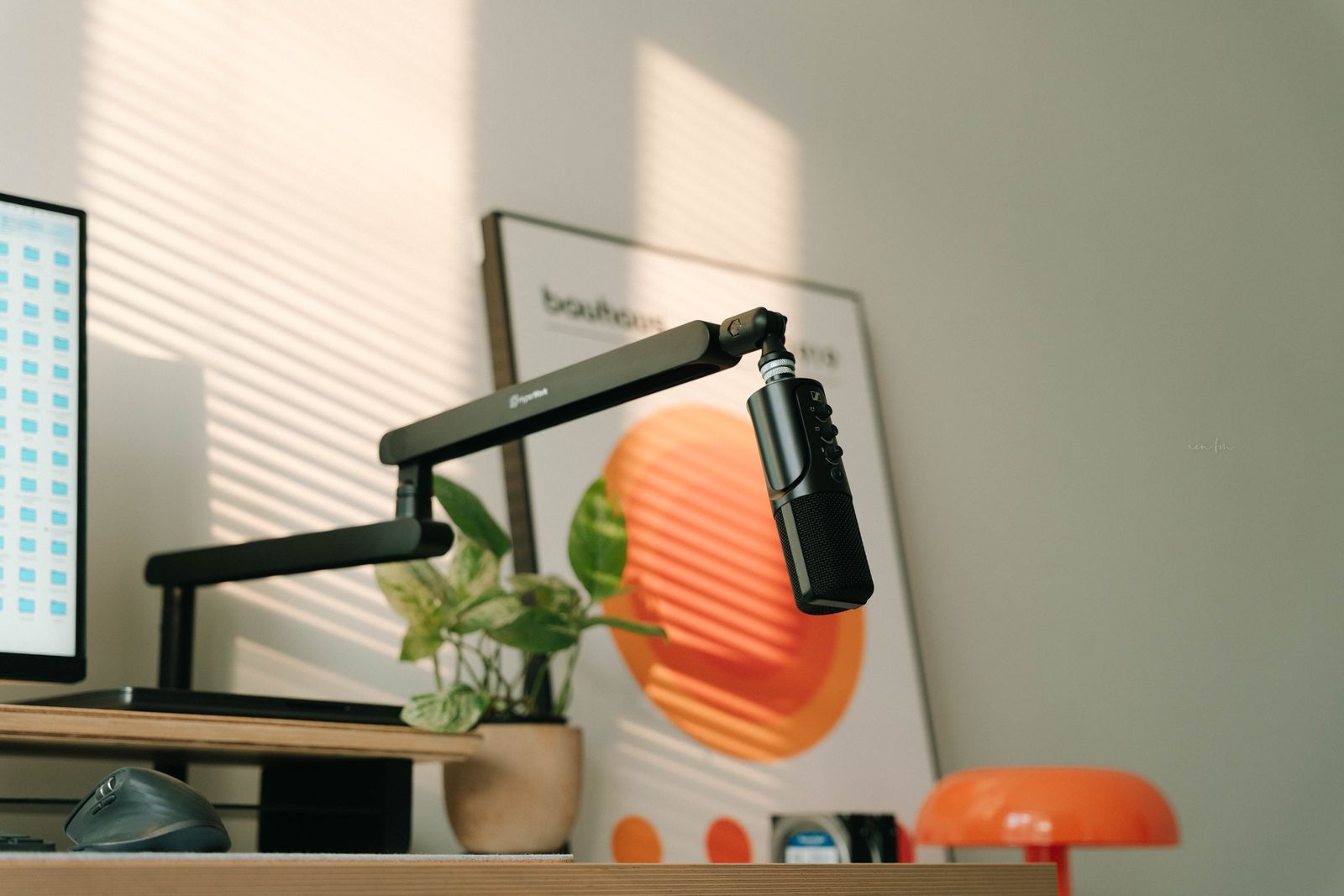 Microphone de podcast sur bras articulé devant une plante et un poster